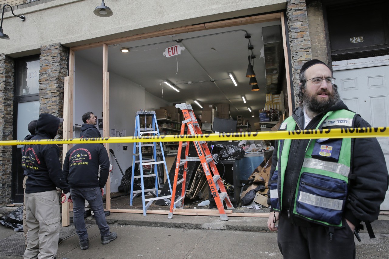CORRECTS PHOTOGRAPHER TO SETH WENIG - People work to secure the scene of a shooting at a kosher supermarket in Jersey City, N.J., on Wednesday, Dec. 11, 2019. Jersey City mayor Steven Fulop refused to call it an anti-Semitic attack but said surveillance video showed the gunmen driving slowly through the city's streets and then stopping outside a kosher grocery store, where they calmly got out of their van and immediately opened fire. (AP Photo/Seth Wenig)