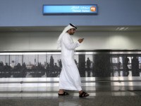 FILE - In this Oct. 27, 2013 file photo, a worker looks at his mobile phone at the newly opened Al Maktoum International Airport in Dubai, United Arab Emirates. According to a New York Times report, ToTok, a chat app that quickly became popular in the United Arab Emirates for …