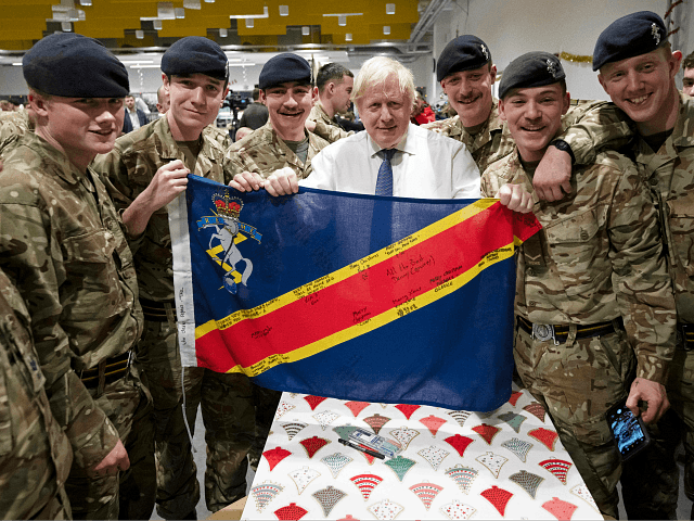 Britain's Prime Minister Boris Johnson (C) poses with troops after serving Christmas lunch to British troops (The Queen's Royal Hussars) stationed in Estonia at the Tapa military base on December 21, 2019, during a one-day visit to the Baltic country. - Tapa military base is home to 850 British troops …