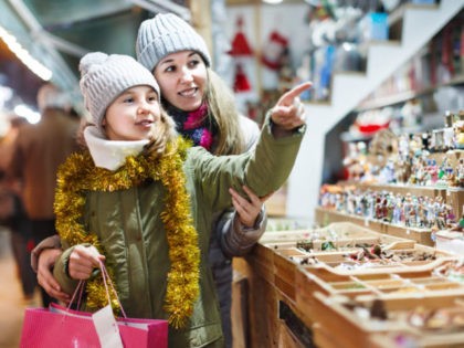 Smiling girl with woman are preparing for a Christmas and choosing a gifts for a their family outdoor. Focus on child