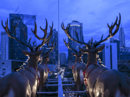 This picture taken on December 5, 2018 shows the iconic Pertonas Twin Towers at right seen from a hanging restaurant suspended by a crane overlooking the skyline of Kuala Lumpur inspired by Santa Claus travelling on a sleigh with reindeers for a Christmas season promotion. - Strapped into rollercoaster-like seats, …