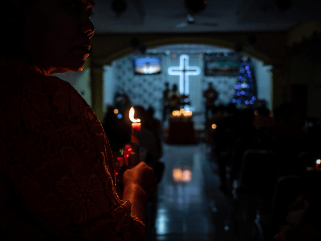 Christians hold candles during Christmas Eve mass at a church in Carita, Banten province,