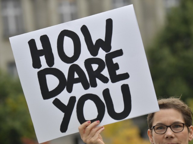 An environmentalist holds up a poster reading "How dare you", quoting Swedish teenage climate activist Greta Thunberg, as she protests outside the German Chancellery where is taking place the weekly cabinet meeting in Berlin on September 25, 2019. (Photo by Tobias SCHWARZ / AFP) (Photo credit should read TOBIAS SCHWARZ/AFP …
