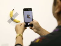 People post in front of Maurizio Cattelan's "Comedian" presented by Perrotin Gallery and on view at Art Basel Miami 2019 at Miami Beach Convention Center on December 6, 2019 in Miami Beach, Florida. Two of the three editions of the piece, which feature a banana duct-taped to a wall, have …
