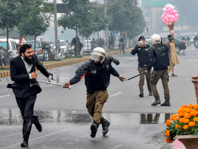 A policeman chases a lawyer (L) following a clash between lawyers and doctors in Lahore on