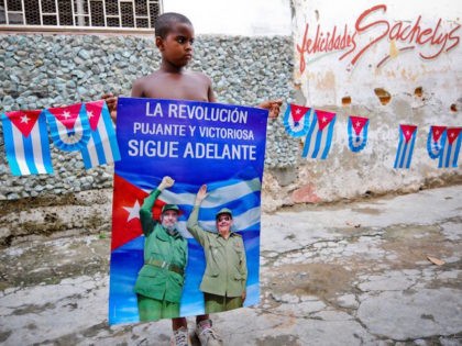 A Cuban boy holds a poster of Cuban president Raul Castro and Cuban former president Fidel Castro, on August 12, 2014 in Havana. Fidel Castro will be 88 on Wednesday. AFP PHOTO/YAMIL LAGE (Photo credit should read YAMIL LAGE/AFP via Getty Images)