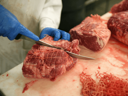 A butcher cuts into a piece of veal at a meat packing and distribution facility June 24, 2