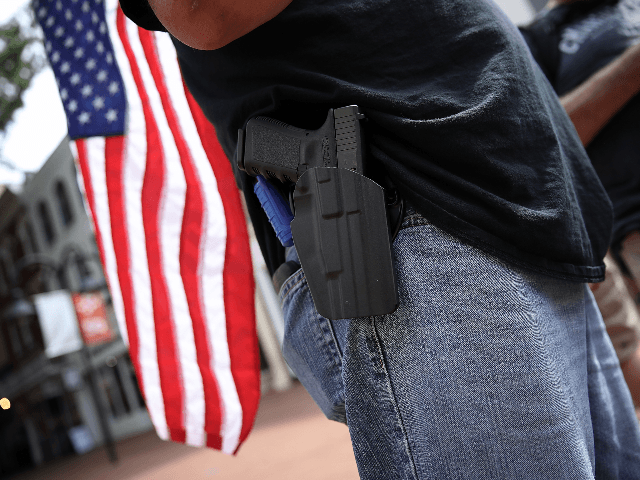 A protester wearing a pistol on his hip stands near the location where a car plowed into a crowd of protestors marching through a downtown shopping district August 12, 2017 in Charlottesville, Virginia. The car allegedly plowed through a crowd, and at least one person has died from the incident, …