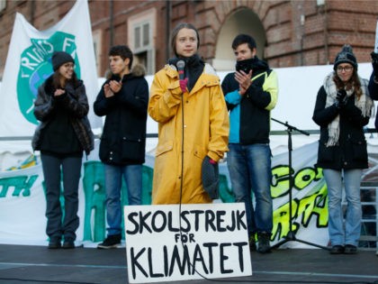 Swedish environmental activist Greta Thunberg attends a climate march, in Turin, Italy, Friday. Dec. 13, 2019. Thunberg was named this week Time's Person of the Year, despite becoming the figurehead of a global youth movement pressing governments for faster action on climate change. Writing on sign at her feet reads …