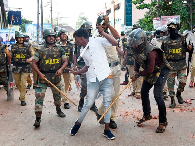 Police clash with a protester during demonstrations against India's new citizenship law in