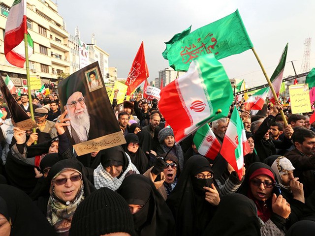 TOPSHOT - Iranian pro-government demonstrators raise national flags and pictures of the Is