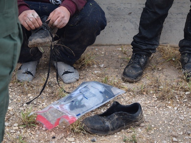 A recently apprehended migrant removes the laces from his shoes before being transported to the Border Patrol station for processing. (Photo: Bob Price/Breitbart Texas)