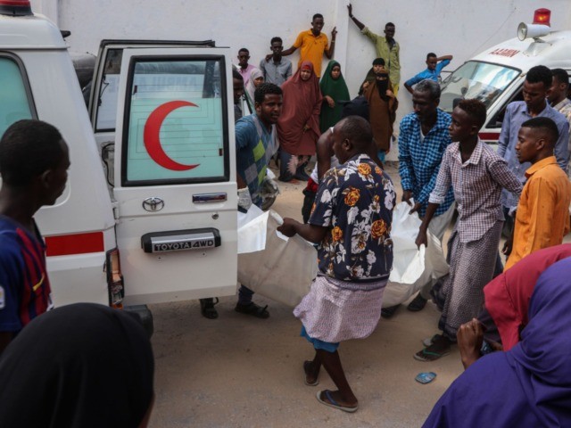 Somali men help to unload a victim, that was injured during a car bombing attack, at the Madina Hospital in Mogadishu, on December 28, 2019. - A massive car bomb exploded in a busy area of Mogadishu on on December 28, 2019, leaving at least 76 people dead, many of …