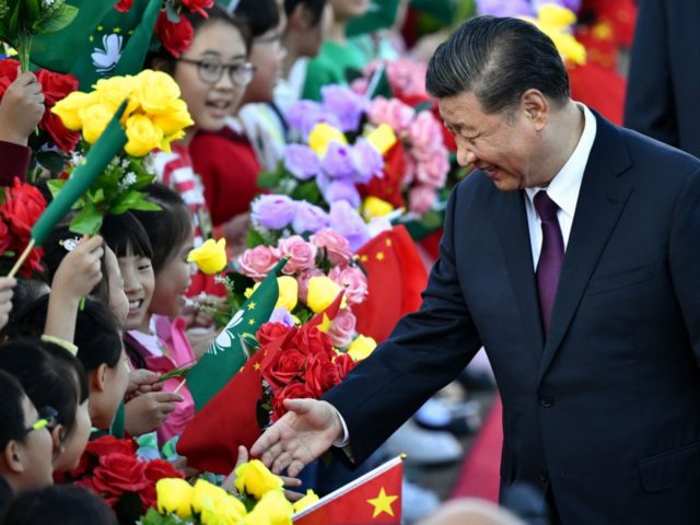 China's President Xi Jinping greets children waving the flags of China and Macau upon his