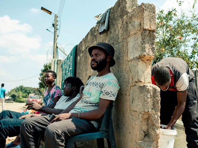 Peter John Vinyu (C) who is unemployed sits among his friends along a road in Highfield to