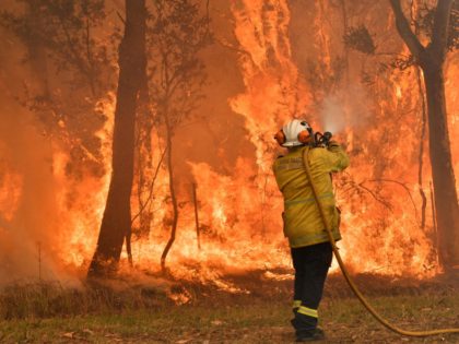 TOPSHOT - A firefighter conducts back-burning measures to secure residential areas from encroaching bushfires in the Central Coast, some 90-110 kilometres north of Sydney on December 10, 2019. - Toxic haze blanketed Sydney on December 10 triggering a chorus of smoke alarms to ring across the city, as Australians braced …