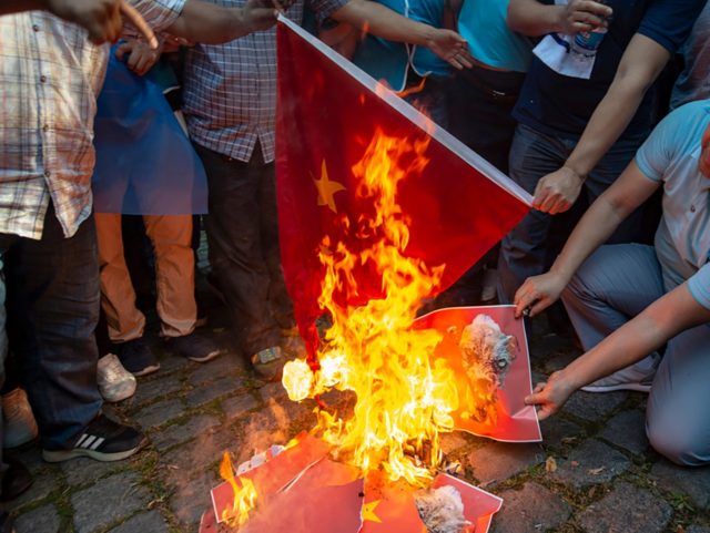 Supporters of China's Muslim Uighur minority and Turkish nationalists burn a Chinese flag