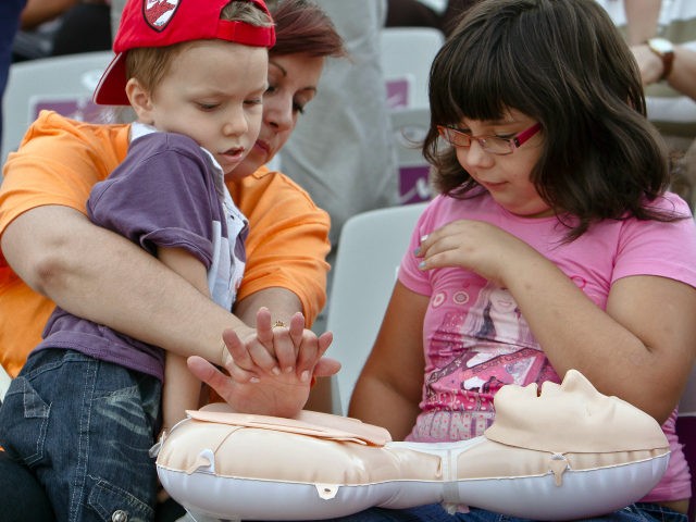 Children are shown CPR techniques on a dummy during a training organized by Romania's ambu