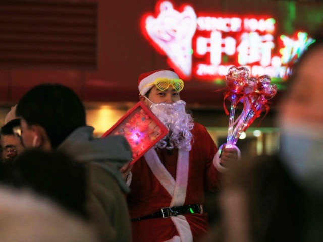 This photo taken on December 24, 2019 shows a vendor dressed as Santa Claus selling toys o