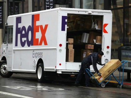 SAN FRANCISCO, CALIFORNIA - DECEMBER 02: A FedEx worker stacks packages on a cart on Decem