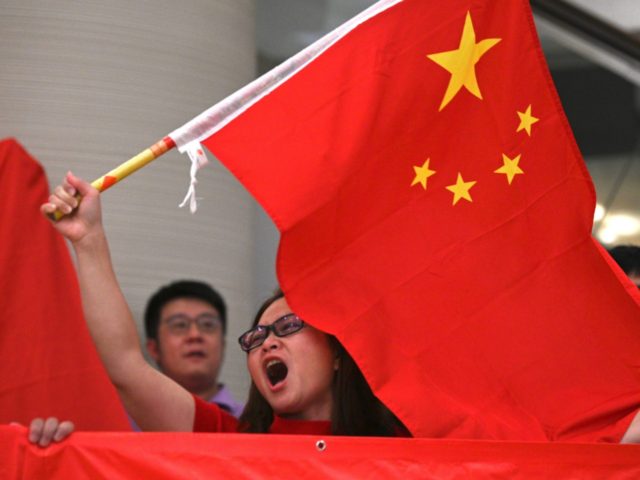 A woman sings and waves the national flag of China during a pro-Beijing flash mob at the P