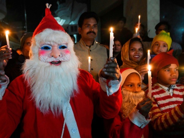 Christian devotees dressed as Santa Claus hold candles as they take part in a procession a