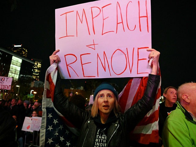 Jamie Jackson (C) protests as she holds a sign and the US flag calling for the impeachment of US President Donald Trump outside the Los Angeles City Hall building, in Los Angeles, California on December 17, 2019. (Photo by Robyn Beck / AFP) (Photo by ROBYN BECK/AFP via Getty Images)