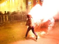 An anti-government protester throws flares against the riot police, background, during a protest near the parliament square, in downtown Beirut, Lebanon, Sunday, Dec. 15, 2019. Lebanese security forces fired tear gas, rubber bullets and water cannons Sunday to disperse hundreds of protesters for a second straight day, ending what started …