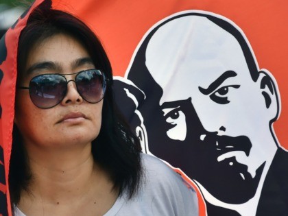 A Russian Communists' supporter stands by a flag picturing Vladimir Lenin, the founder of the Union of Soviet Socialist Republics (USSR), during a rally in downtown Moscow on August 22, 2016, to mark the symbolic 25th anniversary of the August 1991 putsch. On August 19, 1991, a group of security …