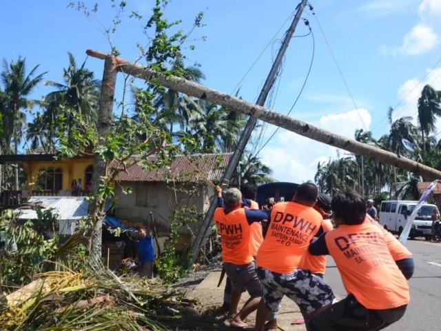 Workers pull a fallen electric pylon damaged at the height of Typhoon Phanfone in Salcedo