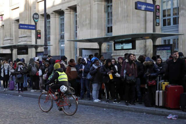 France Strikes A woman rides her bicycle as commuters wait for a bus at Gare du Nord Station, in Paris, Tuesday, Dec. 10, 2019. Only about a fifth of French trains ran normally Tuesday, frustrating tourists finding empty train stations, and most Paris subways were at a halt. French airport workers, teachers and others joined nationwide strikes Tuesday as unions cranked up pressure on the government to scrap changes to the national retirement system. (AP Photo/Francois Mori) The Associated Press
