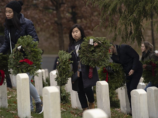 Volunteers arrive to lay holiday wreaths at headstones in Arlington National Cemetery during Wreaths Across America Day in Arlington, Va., Saturday, Dec. 14, 2019. Maine businessman Morrill Worcester started the annual event in 1992 at Arlington National Cemetery, and it has expanded to hundreds of veterans' cemeteries and other locations …