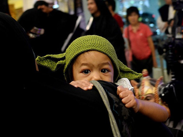 A young Malaysian dressed as baby Yoda clings on to her mother during an event to mark the