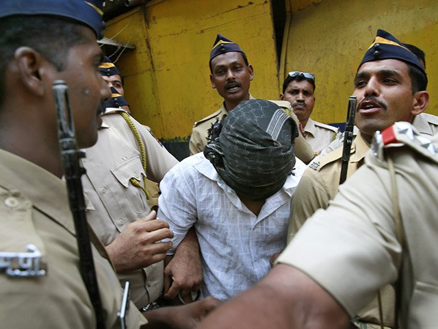 Police officers escort one of the four convicts in the gang rape of a photojournalist outside a prison to be taken to a court in Mumbai, India, Wednesday, March 26, 2014. An Indian court convicted the four last week for raping a photojournalist inside an abandoned textile mill in the …