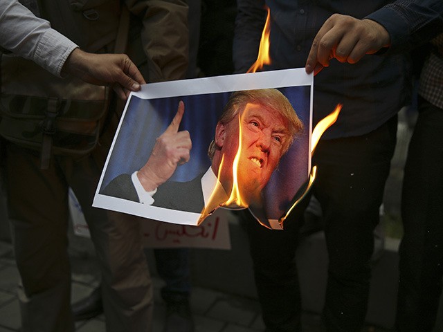 Demonstrators burn a picture of U.S. President Donald Trump during during a protest in fro