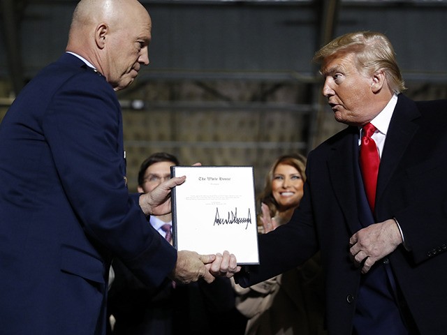 President Donald Trump shakes hands with Gen. Jay Raymond, after signing the letter of his