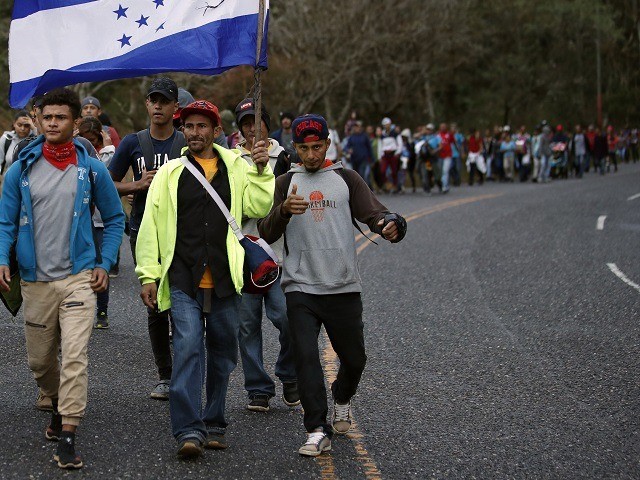 Honduran migrants walk north along a road in hopes of reaching the distant United States, one carrying a Honduran flag, as they leave Esquipulas, Guatemala, just after sunrise Friday, Jan. 17, 2020. The group departed San Pedro Sula on Jan. 15. (AP Photo/Moises Castillo)