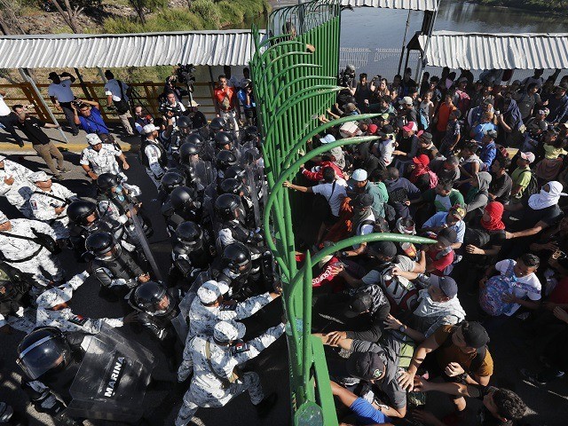 Migrants charge on the Mexican National Guardsmen at the border crossing between Guatemala