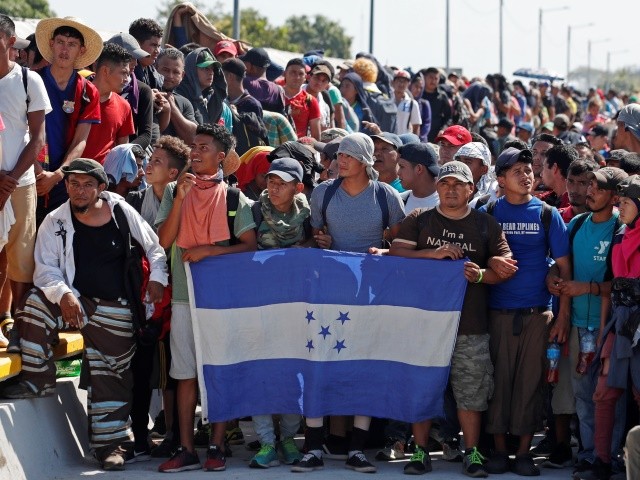 Central American migrants holding Honduras' national flag stand on the legal border crossing bridge over the Suchiate River that connects Tecun Uman, Guatemala with Ciudad Hidalgo, Mexico, Monday, Jan. 20, 2020. (AP Photo/Moises Castillo)
