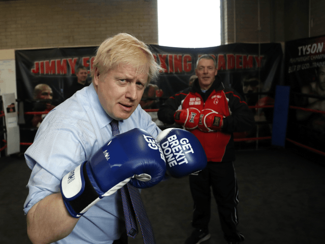 MANCHESTER, ENGLAND - NOVEMBER 19: Britain's Prime Minister Boris Johnson poses for a photo wearing boxing gloves emblazoned with "Get Brexit Done" during a stop in his General Election Campaign trail at Jimmy Egan's Boxing Academy on November 19, 2019 in Manchester, England. Britain goes to the polls on Dec.12. …