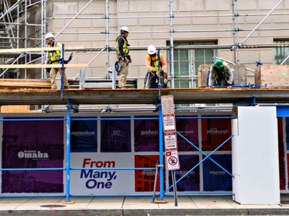 Construction workers put up support scaffolding on the side of a building in Washington, D