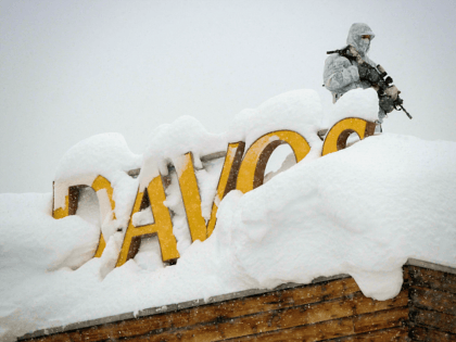 TOPSHOT - An armed security personnel wearing camouflage clothing stands on the rooftop of a hotel, next to letters covered in snow reading "Davos", near the Congress Centre ahead of the opening of the 2018 World Economic Forum (WEF) annual summit on January 22, 2018 in Davos, eastern Switzerland. The …