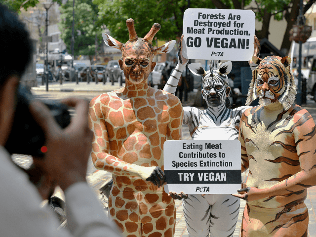 Indian animal rights activists with the group PETA (People for the Ethical Treatment of Animals) dressed as a giraffe, zebra and tiger hold placards during a rally urging the public to save forests by going vegan in Bangalore on March 19, 2019. - March 21 is observed as the International …