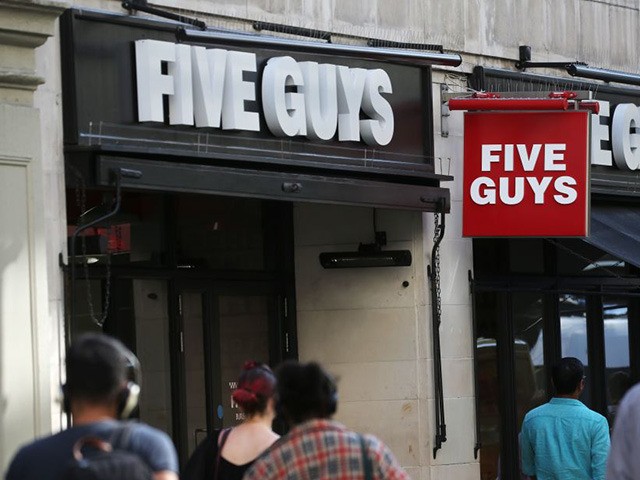 Pedestrians pass a branch of a Five Guys restaurant in London on August 23, 2019. (Photo b