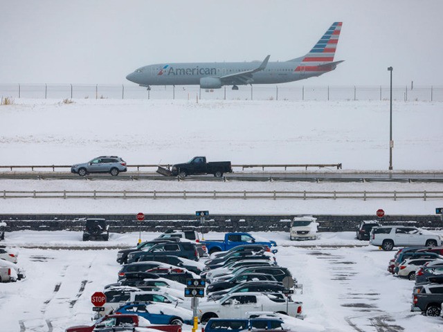 DENVER, CO - NOVEMBER 26: A jet passes snow-covered cars parked at Denver International Ai