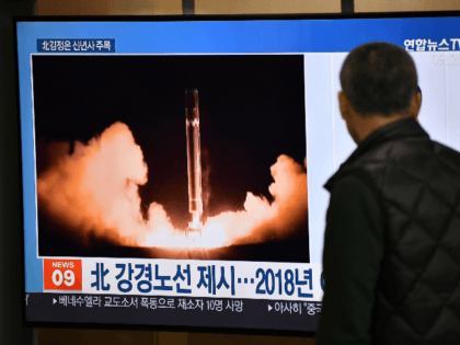 A man watches a television news programme showing file footage of North Korea's missile te