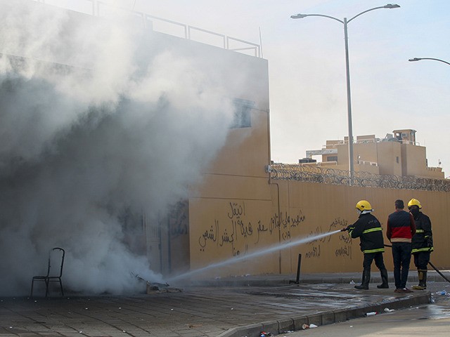 A firefighter extinguishes a flame on the entrance of the US embassy in the Iraqi capital Baghdad on January 1, 2020 during a demonstration by supporters and members of the Hashed al-Shaabi paramilitary force. - Thousands of Iraqi supporters of the largely Iranian-trained Hashed al-Shaabi paramilitary force had gathered at …