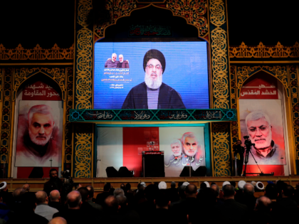 Supporters of the the Shiite Hezbollah movement watch as the movement's leader Hasan Nasrallah delivers a speech on a screen, in the Lebanese capital Beirut's southern suburbs on January 5, 2020. - Nasrallah called on Iraq to free itself of the American "occupation" after top Iranian general Qasem Soleimani was …