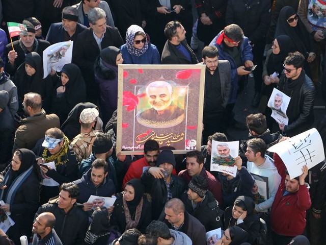 Iranian mourners lift a picture of slain military commander Qasem Soleimani during a funeral procession in the capital Tehran on January 6, 2020, for him as well as Iraqi paramilitary chief Abu Mahdi al-Muhandis and other victims of a US attack. - Downtown Tehran was brought to a standstill as mourners flooded the Iranian capital to pay an emotional homage to Soleimani, the "heroic" general who spearheaded Iran's Middle East operations as commander of the Revolutionary Guards' Quds Force and was killed in a US drone strike on January 3 near Baghdad airport. (Photo by ATTA KENARE / AFP) (Photo by ATTA KENARE/AFP via Getty Images)