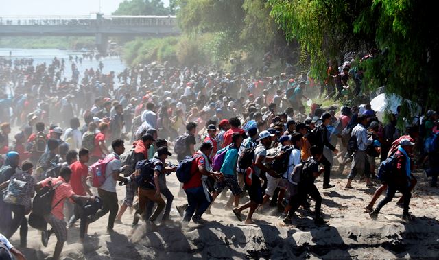Hundreds of Central Americans from a new migrant caravan tried to enter Mexico by force Monday by crossing the river that divides the country from Guatemala, prompting the National Guard to fire tear gas, an AFP correspondent said. (Photo by JOHAN ORDONEZ/AFP via Getty Images)